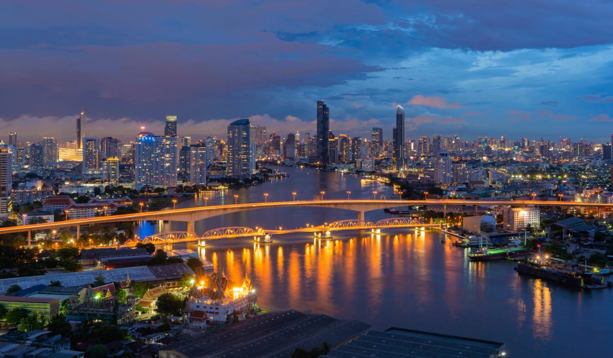 Aerial view of Taksin Bridge with Chao Phraya River, Bangkok Downtown. Thailand. Financial district and business centers in smart urban city. Skyscraper and high-rise buildings at night.
