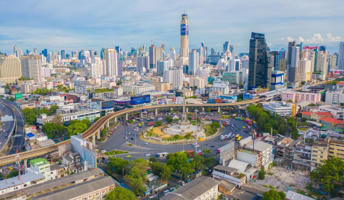 Aerial view of Victory Monument on busy street road. Roundabout in Bangkok Downtown Skyline. Thailand. Financial district center in smart urban city. Skyscrapers at sunset.